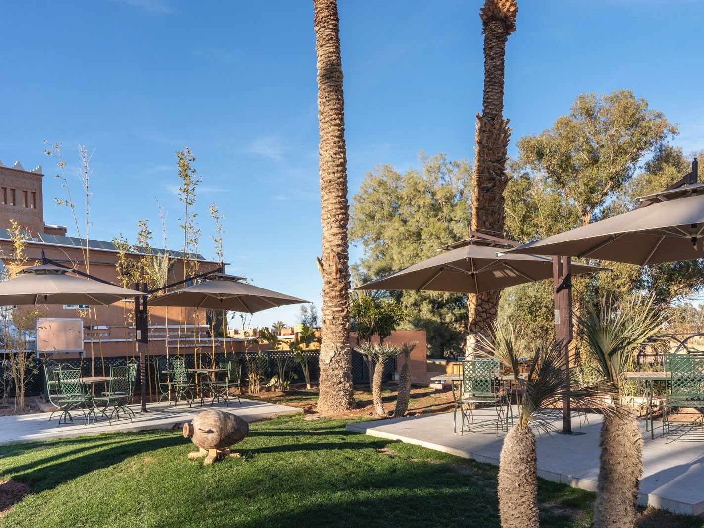 Terrasse du Restaurant Piscine L’Oasis avec tables et palmiers au Kenzi Azghor Ouarzazate.