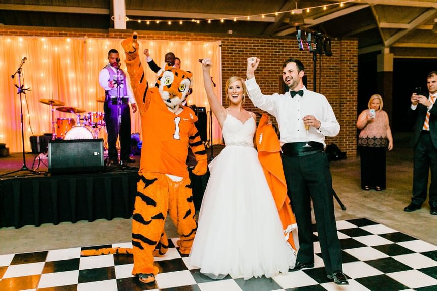 bride and groom celebrating with clemson mascot