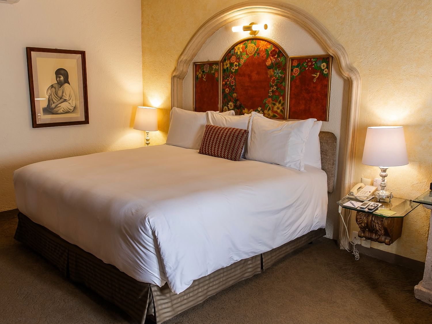 Habitación elegante con cama king, arco decorativo, lámparas de mesa y arte colonial en Quinta Real Zacatecas