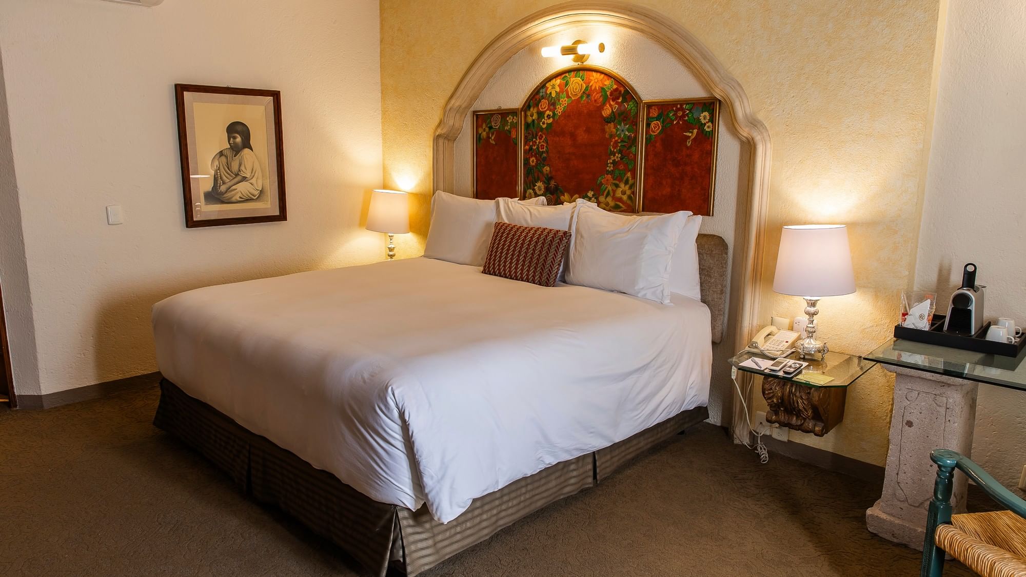 King bed with white linens and decorative headboard in an elegant room at Quinta Real Zacatecas