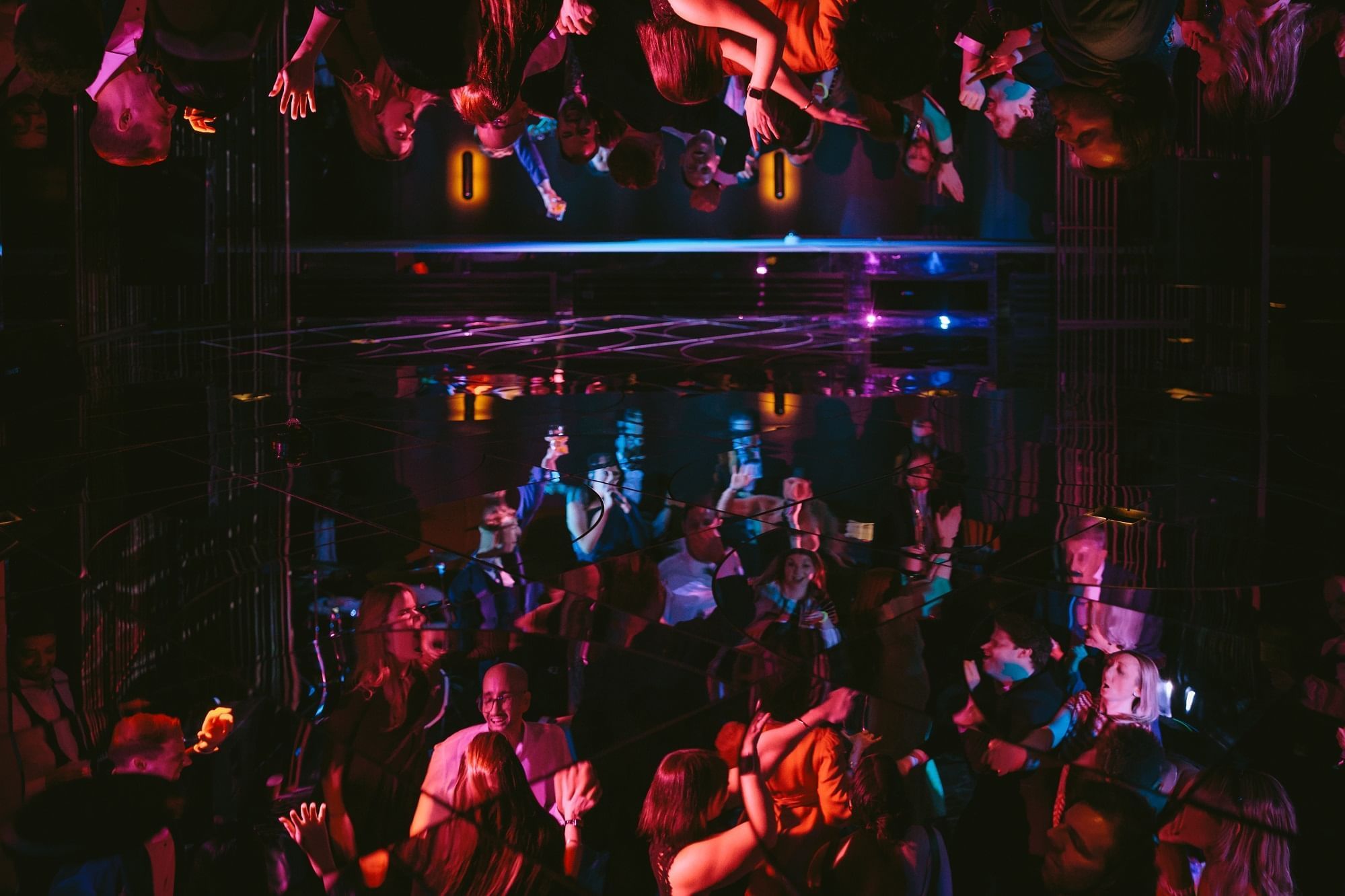 A crowded nightclub with neon lights and dancing people at The Londoner Hotel