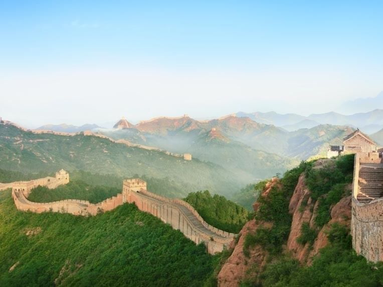 The Great Wall of China winding through green mountains under a clear morning sky near Celebrity International Grand Hotel
