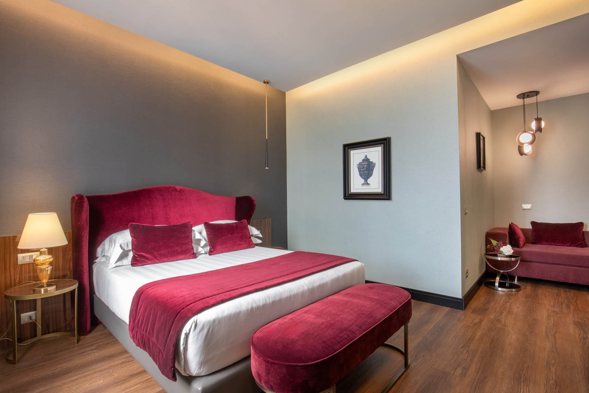 Guardian Suite at The Guardian Hotel with wooden floors, a bed, a matching bench, cozy seating, and elegant lighting