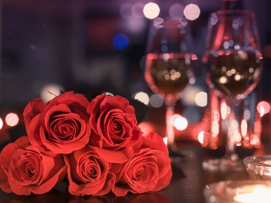 Close-up red roses by glasses of wine on a table at Hotel Grand Chancellor