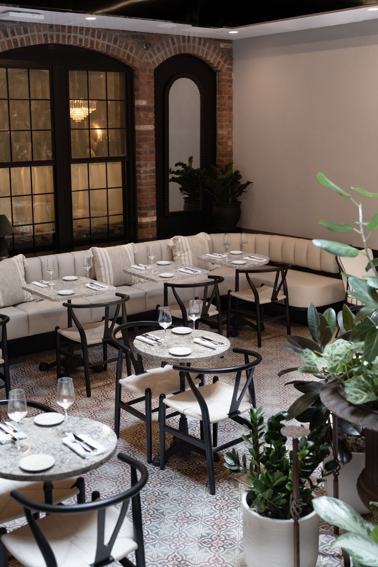 A dining area with booth seating and round tables set with glassware and linens.