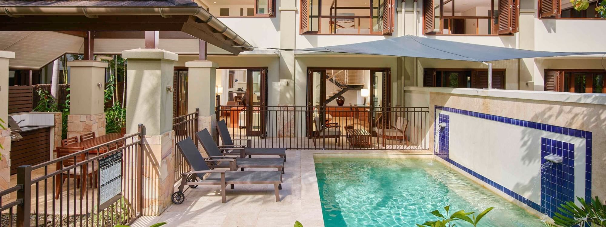Three Bedroom Villas with a pool, sun loungers, and tropical plants at Pullman Port Douglas