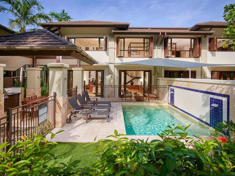 Three Bedroom Villas with a pool, sun loungers, and tropical plants at Pullman Port Douglas