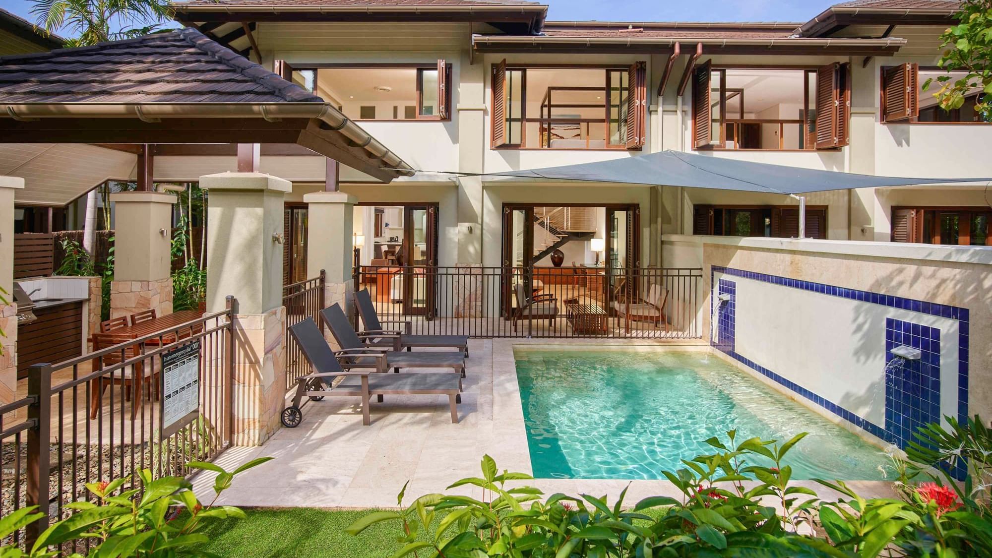 Three Bedroom Villas with a pool, sun loungers, and tropical plants at Pullman Port Douglas