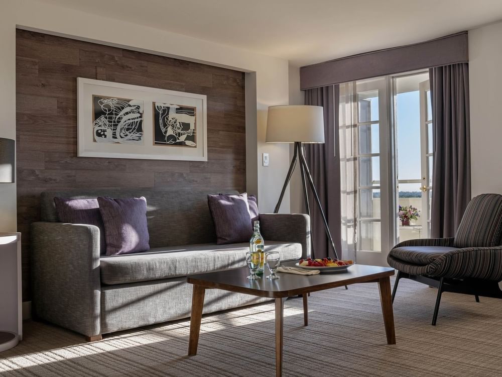 Gray sofa with purple pillows by a tripod lamp under a wood-paneled wall in Executive Suites at Warwick Denver