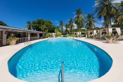 A bright blue outdoor pool with palm trees around on a sunny day at All Seasons Resort Europa