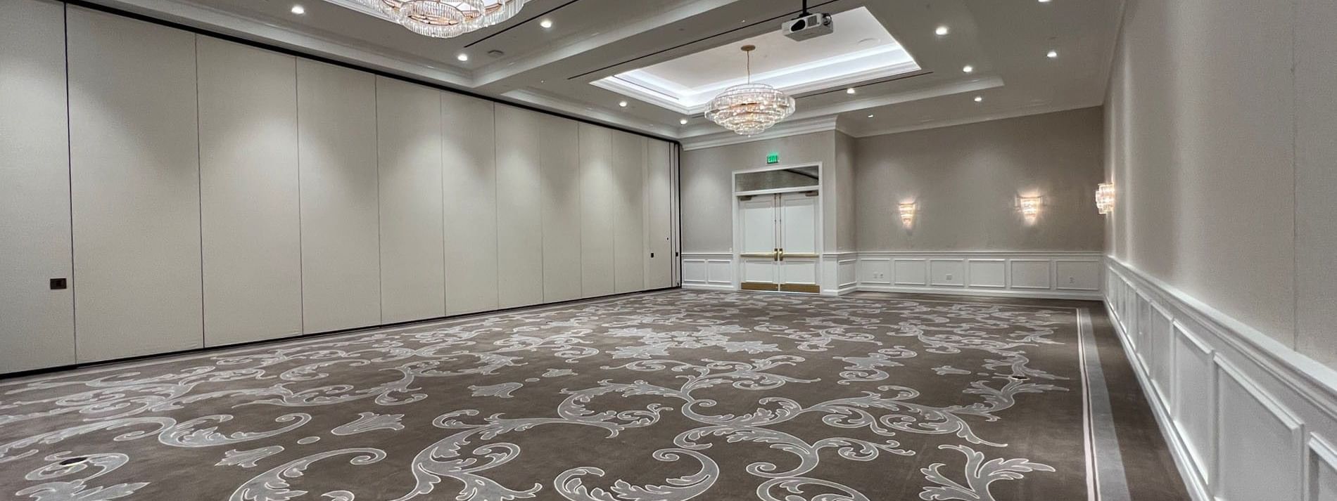 Patterned carpet by a white wall under crystal chandeliers in Turtle Creek Ballroom A at Warwick Melrose Dallas