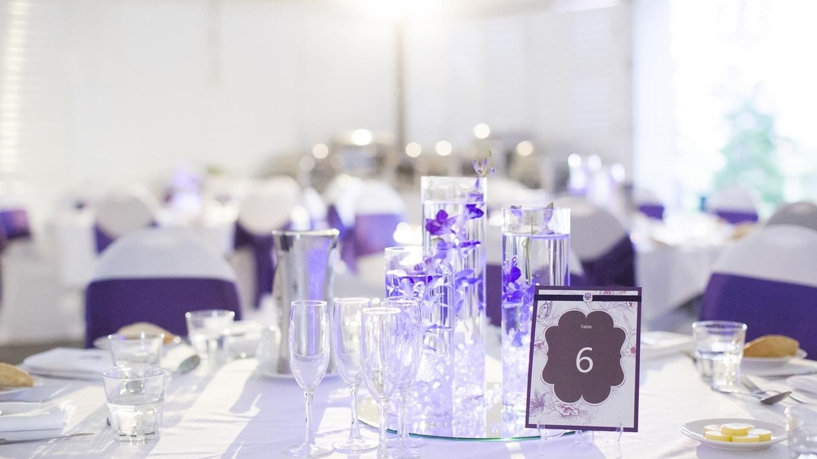 Elegant wedding table set with white & purple accents and soft lighting at Mercure Hotel Townsville