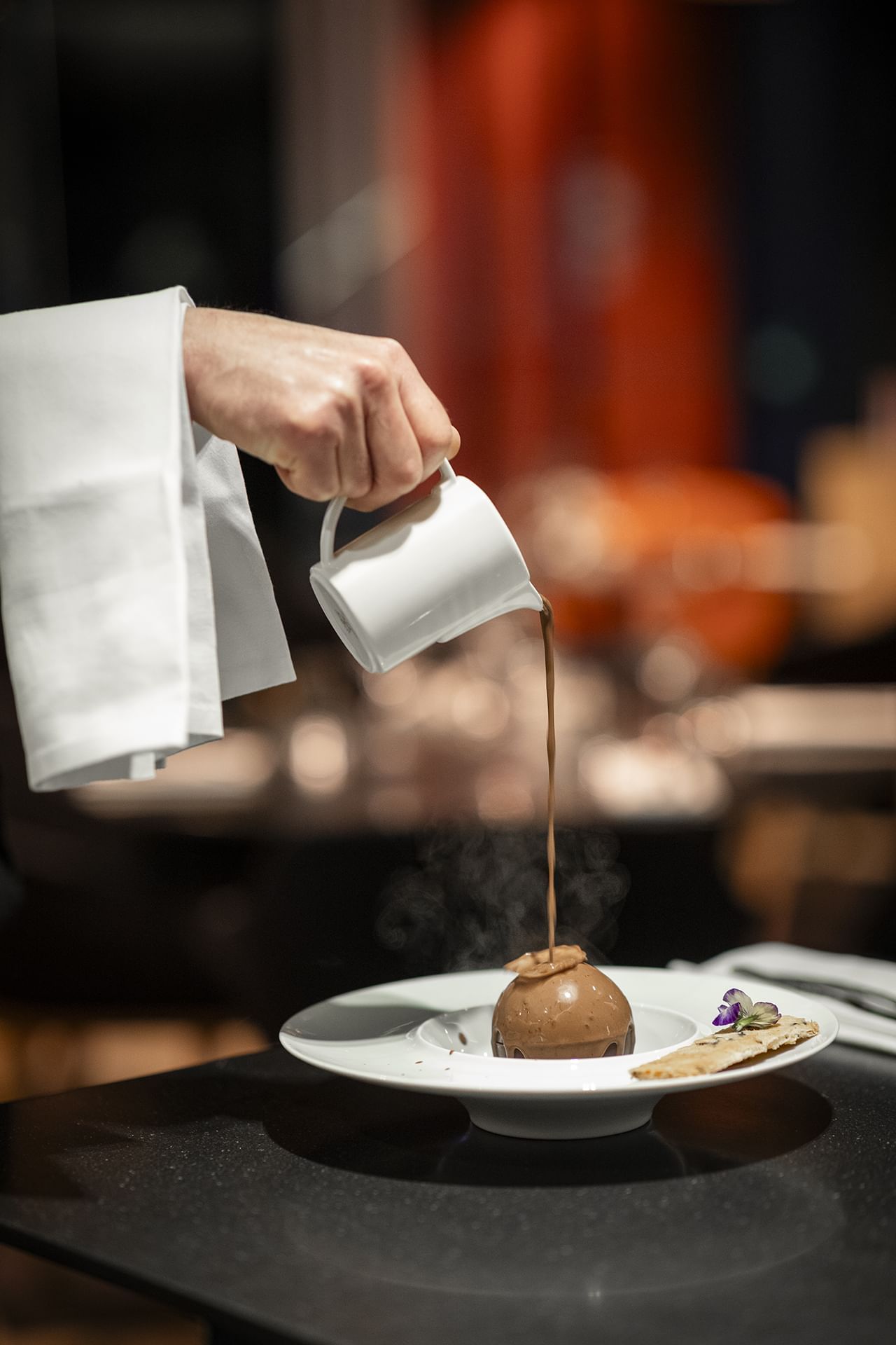 Personne versant du chocolat chaud d'une théière dans une tasse à Oceania Paris Roissy CDG