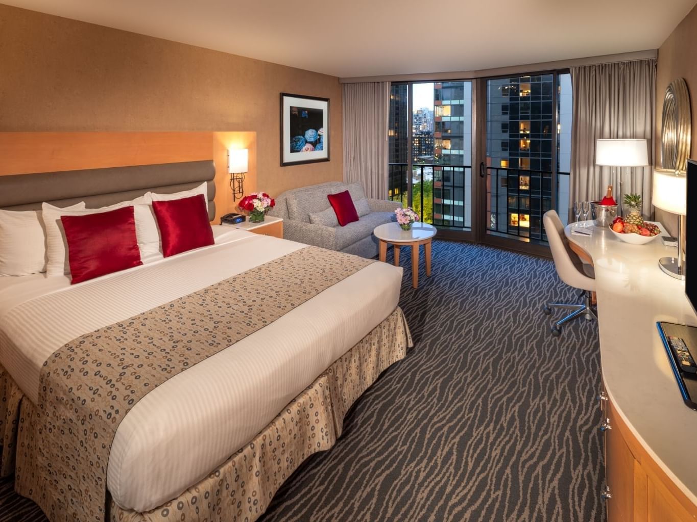 A hotel room with a large bed, a couch, a balcony, and a desk with a TV at Warwick Hotels and Resorts