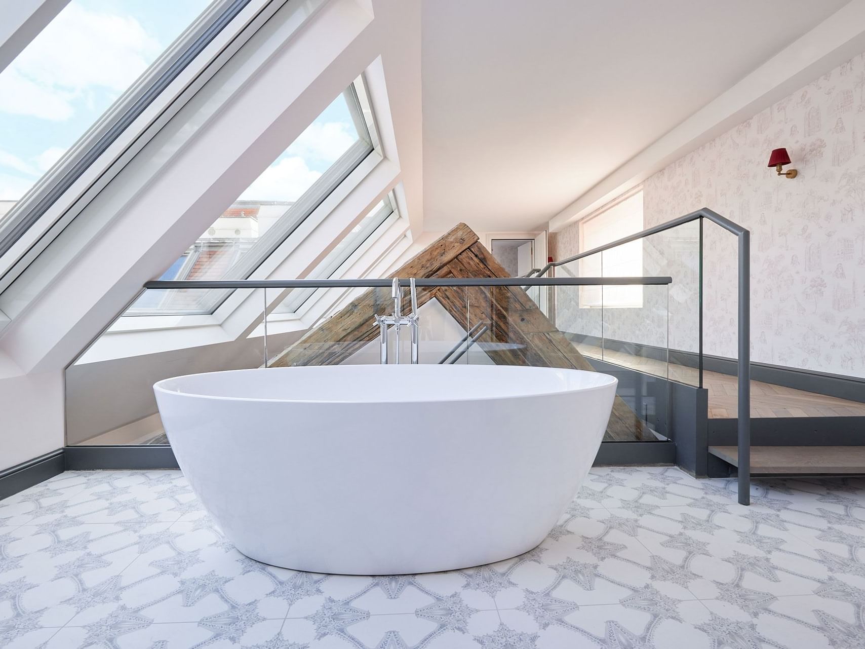 Leopold Suite bathroom with a large freestanding bathtub, glass railings, and skylights allowing natural light.
