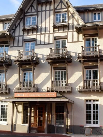 Façade d'un hôtel de style normand avec colombages, balcons en bois et entrée principale au Le Continental Forges 3*.