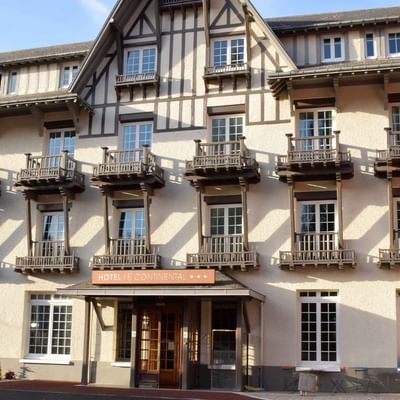 Façade d'un hôtel de style normand avec colombages, balcons en bois et entrée principale au Le Continental Forges 3*.