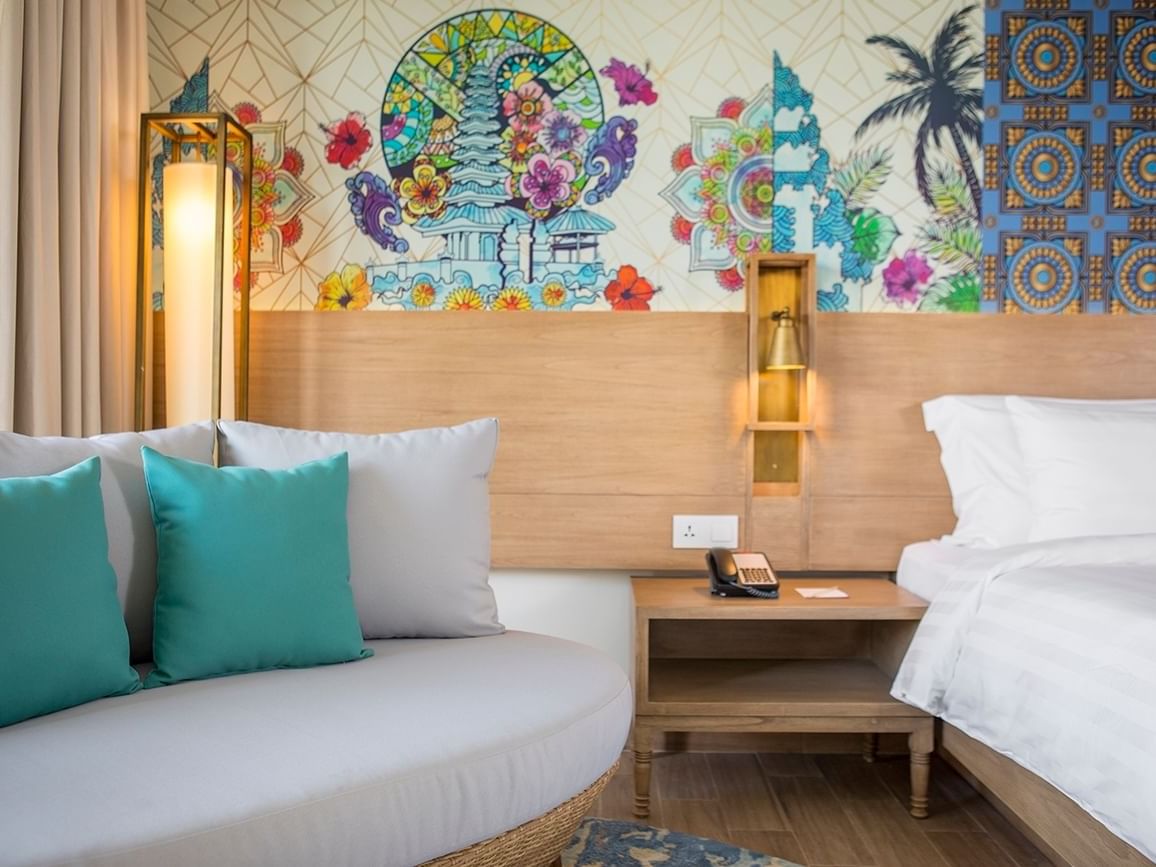 Cozy sofa & bed with wall art in Deluxe Room at Eastin Ashta Resort Canggu