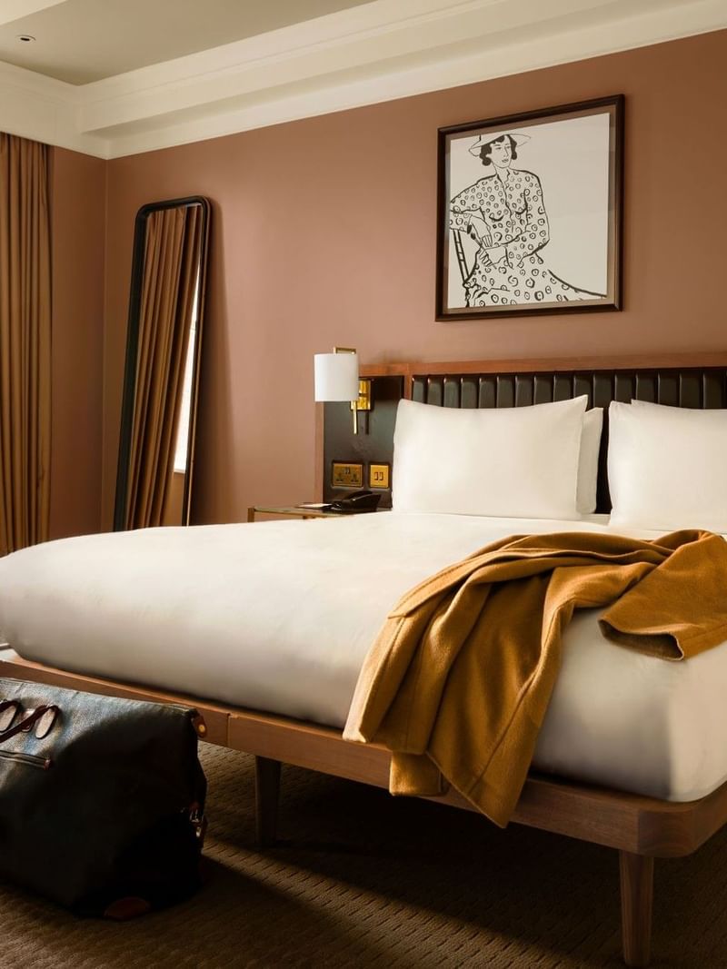 Collection Premium room with a large king bed, with jacket on the bed and overnight bag - showcasing someone staying.