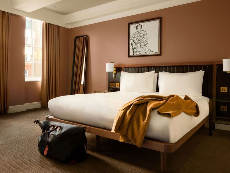 Collection Premium room with a large king bed, with jacket on the bed and overnight bag - showcasing someone staying.