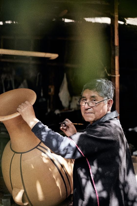 A person painting a huge clay pot  near Hotel Sumaq