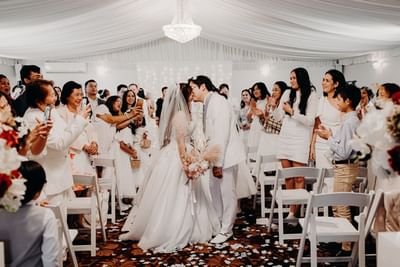 A bride and groom share their first kiss while surrounded by happy guests at the Royal on the Park Hotel
