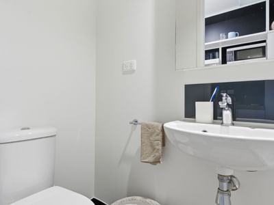 White toilet and sink with towel and soap at UniLodge Auckland City.