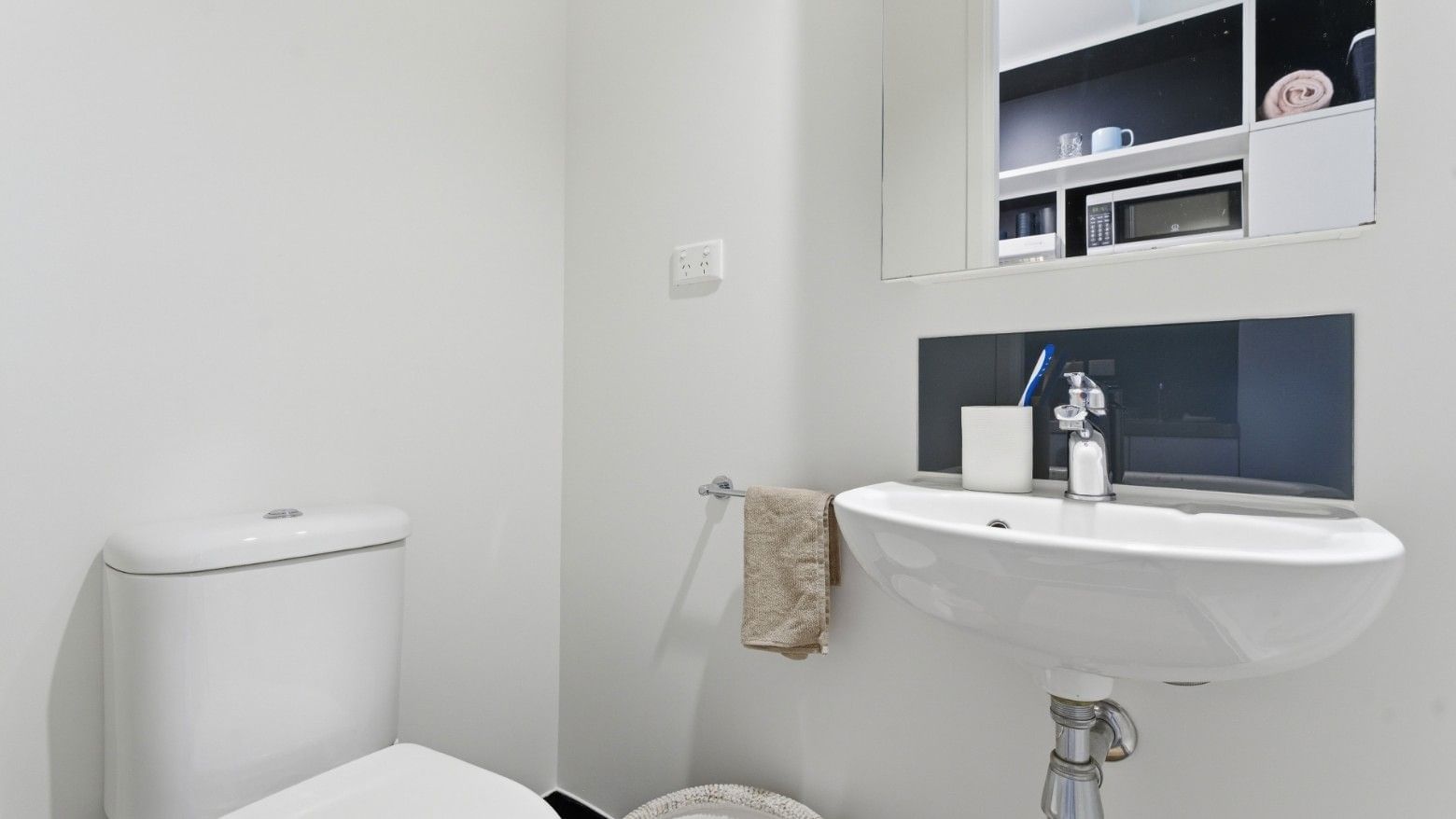 White toilet and sink with towel and soap at UniLodge Auckland City.