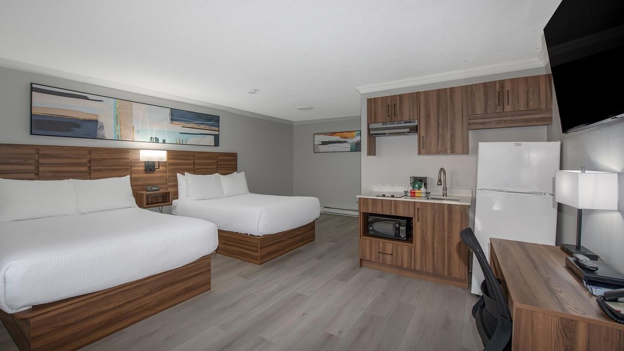 Hotel room with two beds and kitchenette.