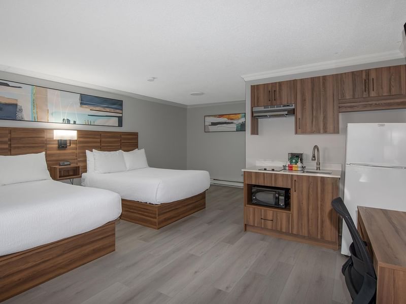 Hotel room with two beds and kitchenette.