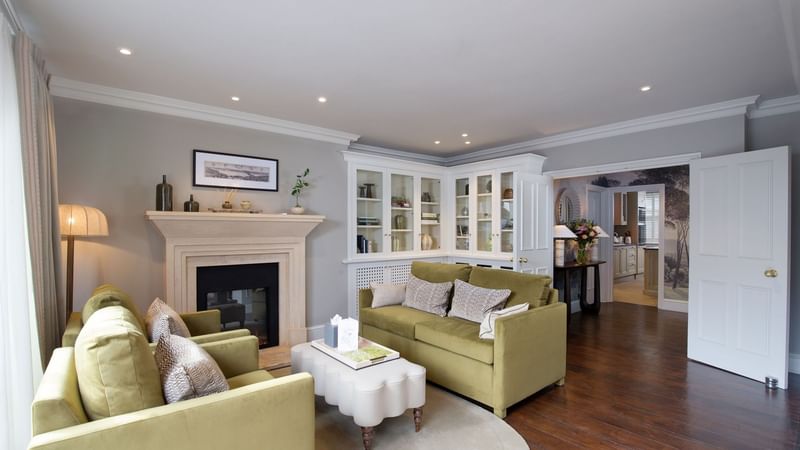 Elegant living room with green couches, fireplace, and wooden floors at The Capital Hotel, Apartments & Townhouse in London.