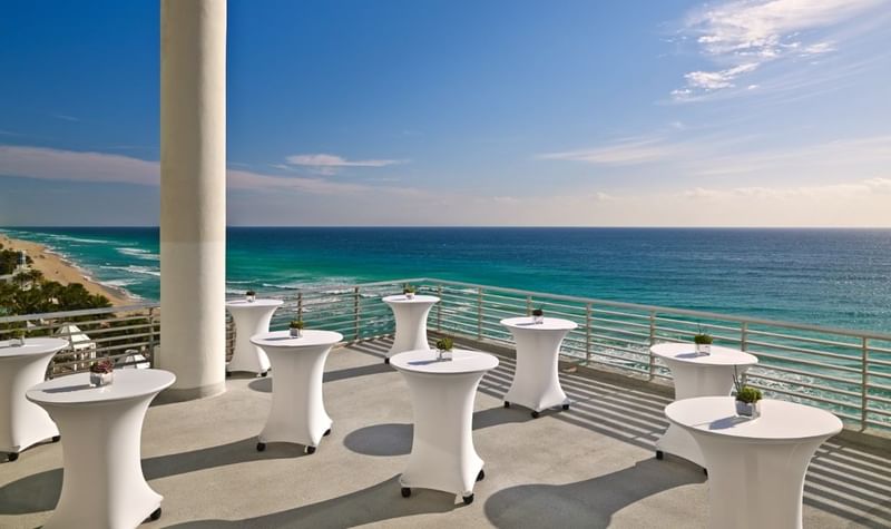 Oceanfront Great Hall Terrace & Foyer at The Diplomat Resort with white tables, sandy beach, and ocean under clear skies