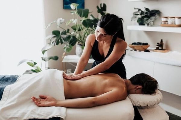 Male getting a back massage on a spa bed by female masseuse
