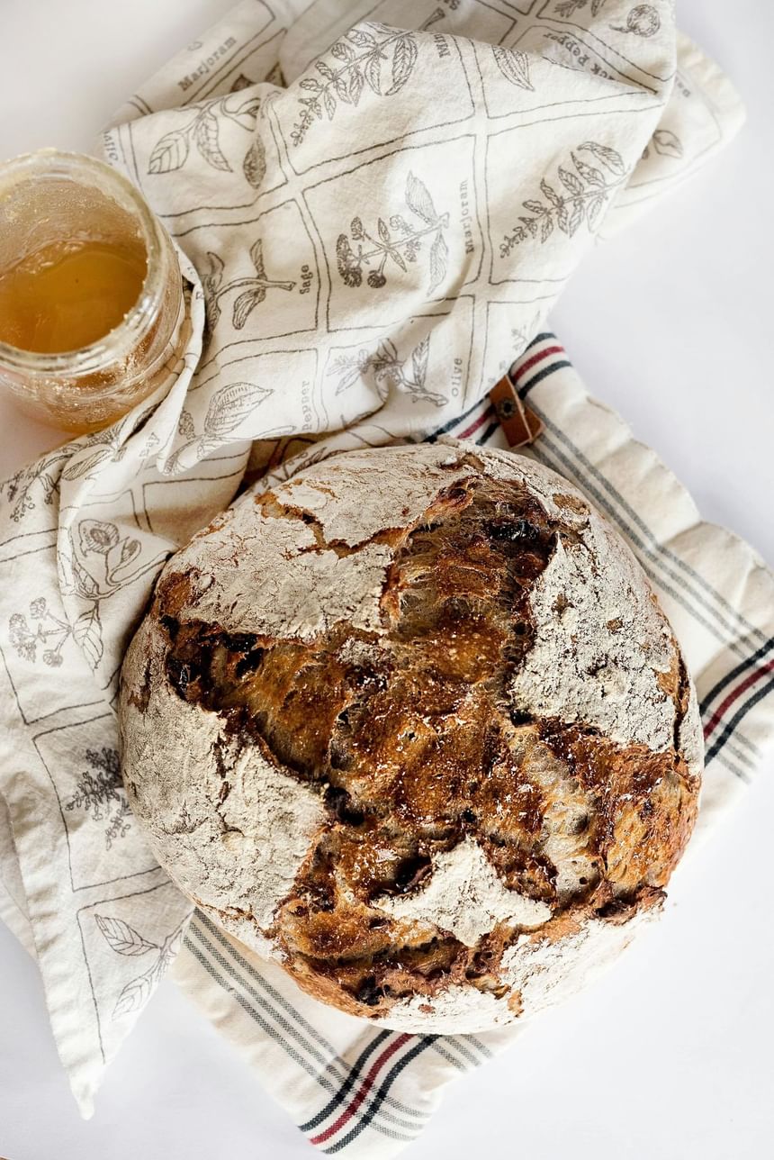 A rusty bread on a cloth next to a honey jar at Hotel Brookmere