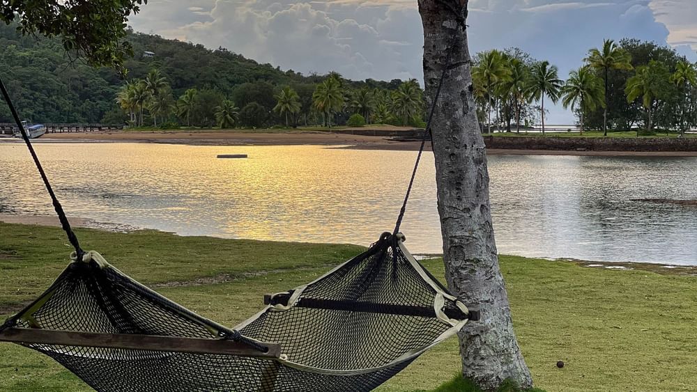 Hammock on grass overlooking a beach at sunset at The Naviti Resort in Korolevu Fiji.