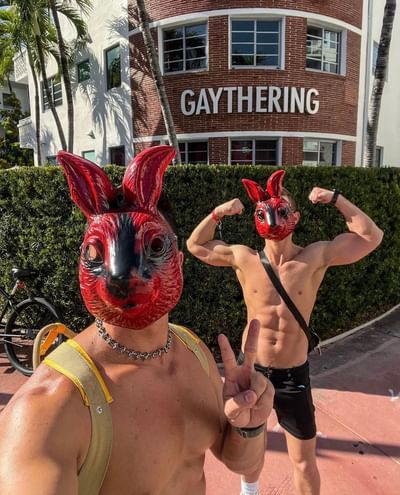 Two men wearing vibrant red bunny masks pose in front of The Gaythering, showcasing playful energy. 