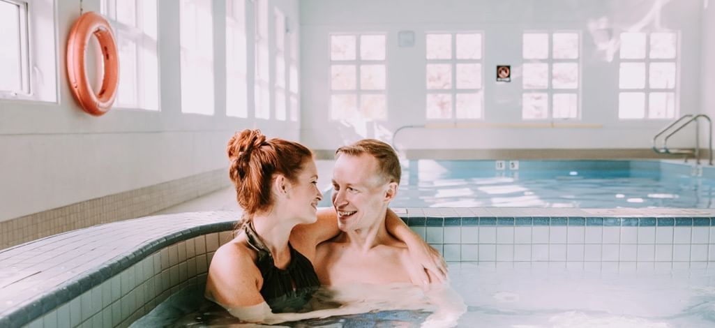 A smiling couple enjoying a romantic moment in the hot tub at Coast Canmore Hotel & Conference Centre.