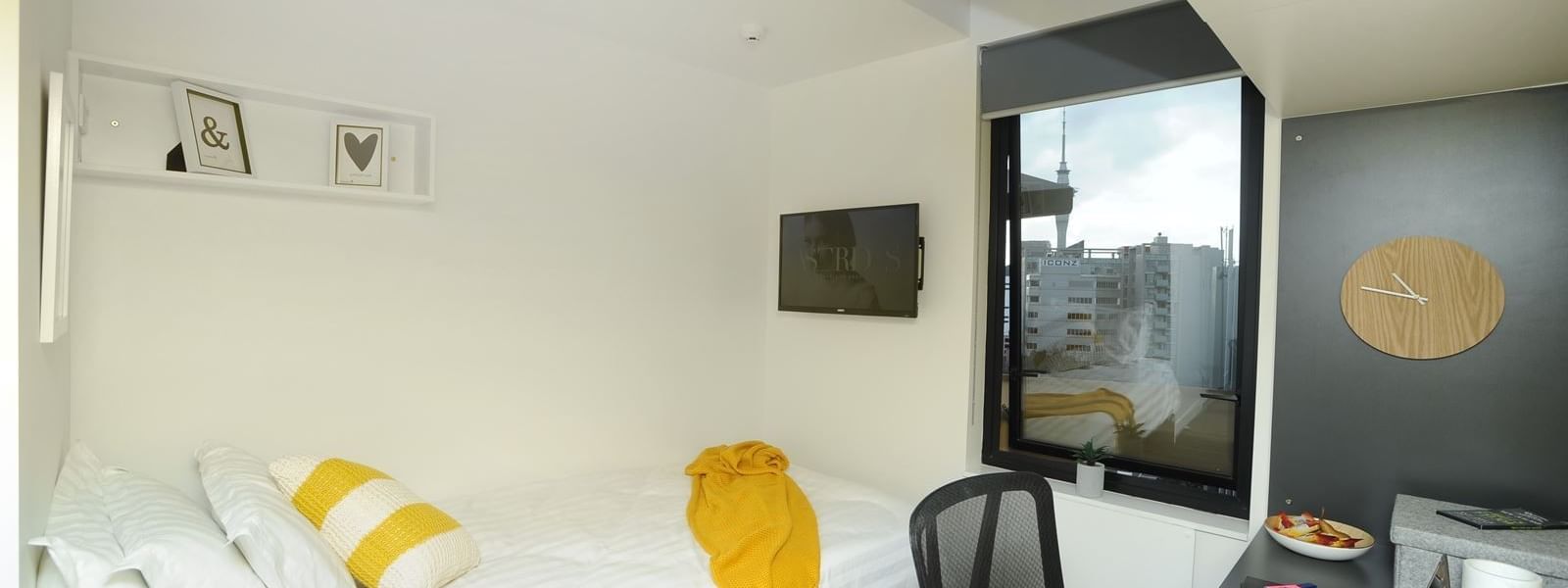 Studio Apartment at UniLodge Auckland City in Grafton with bed, desk, and cityscape view.
