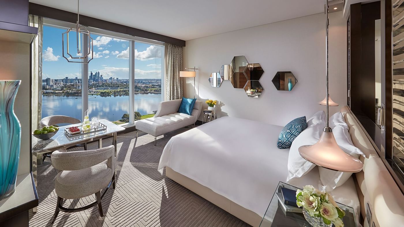King bed, lounge area and work desk overlooking the city and river at Crown Hotels