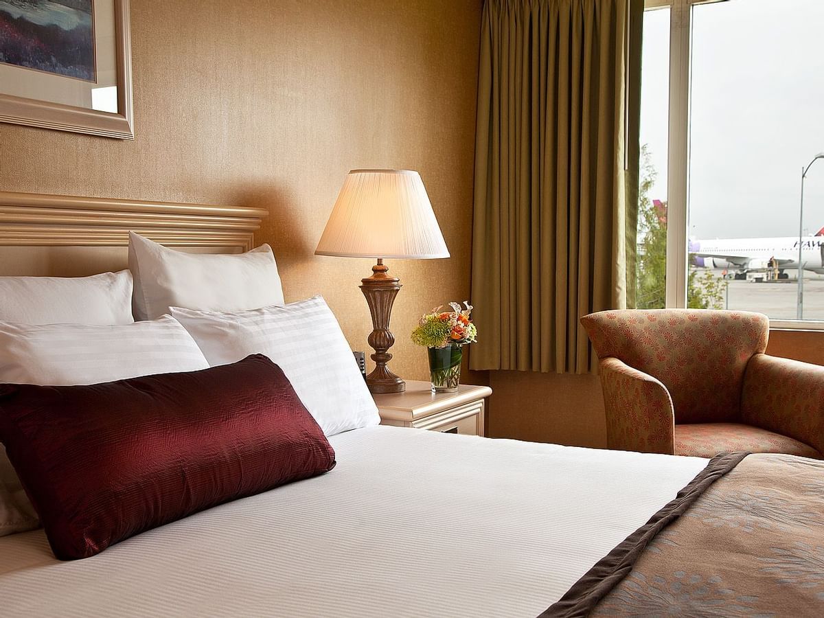 Bed and sofa chair in hotel room with view of airport