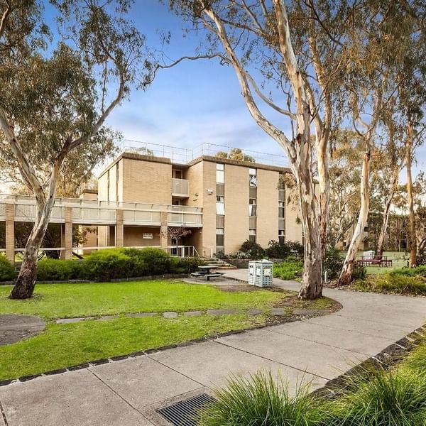 La Trobe University - Glenn College campus view with picnic tables and tall trees.