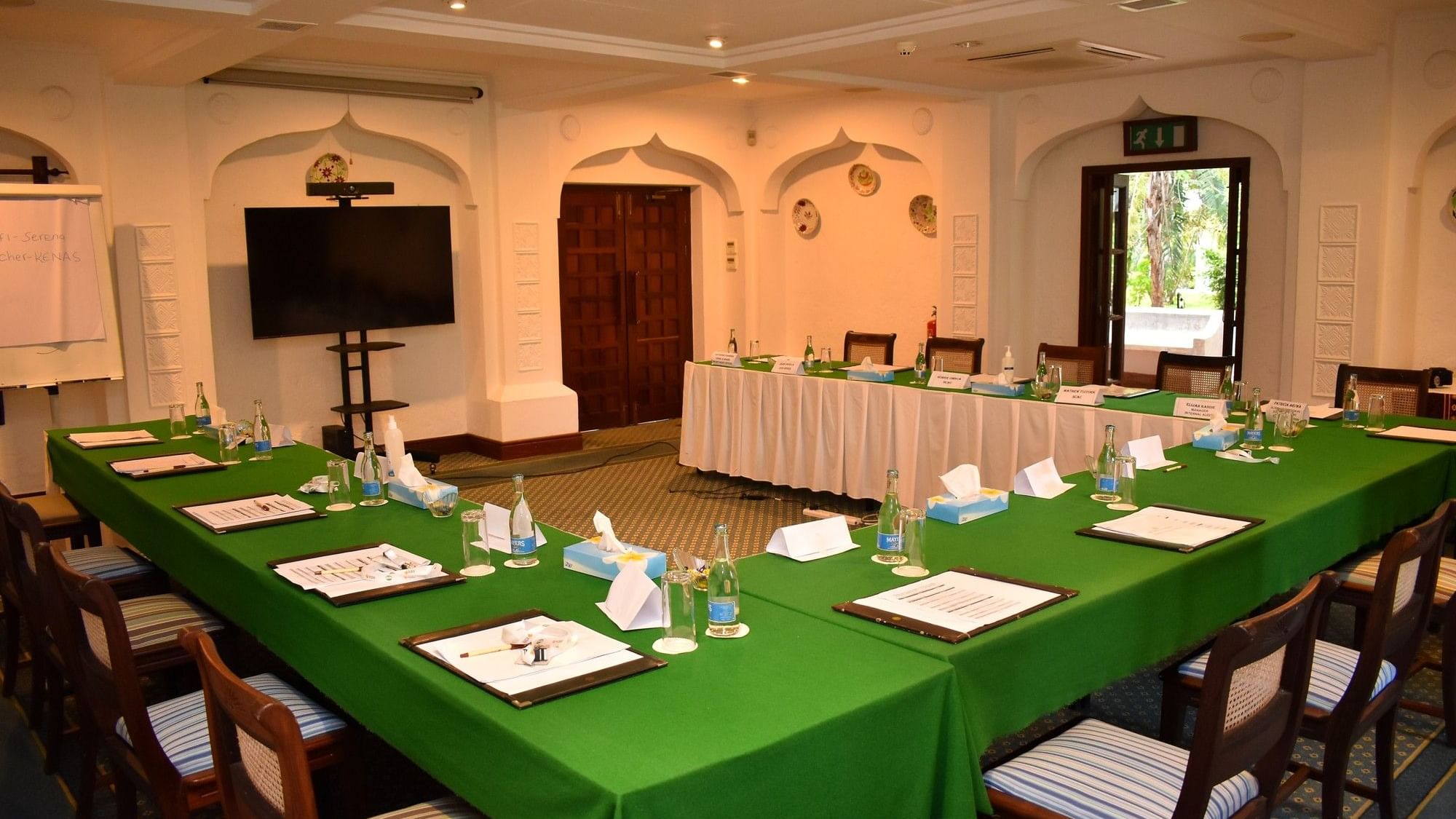 Green conference tables and chairs with papers and bottles in Desert Rose event room at Serena Beach Resort & Spa, Mombasa.