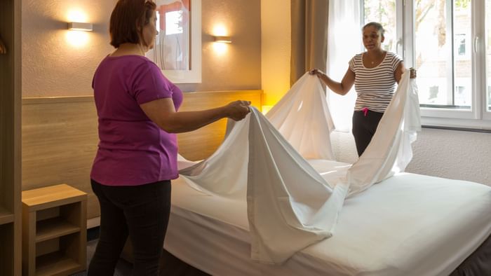 Maids preparing a bed in a room at Hotel Les Oceanes