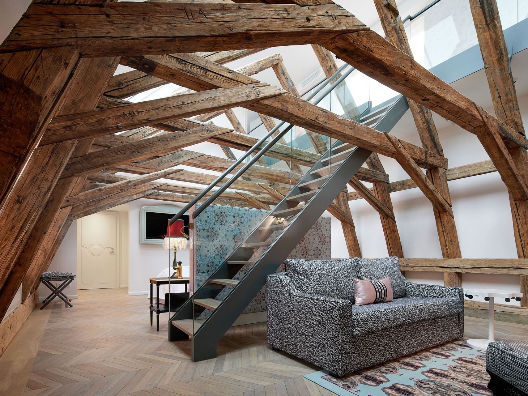 Leopold Suite with a couch, a glass staircase, and exposed wooden beams in the ceiling.