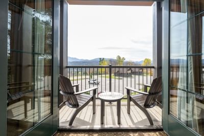 The private balcony at Lake Placid Club Grandview offers two Adirondack chairs and a table with views of the mountains