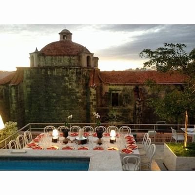 Terraza Rooftop dining set-up beside a pool with a historic stone building and a domed roof at Billini Hotel Historic Luxury
