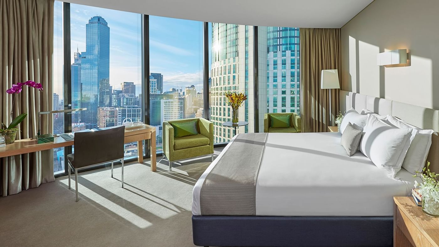 King bed, lounge area and work desk overlooking the city view at Crown Hotels