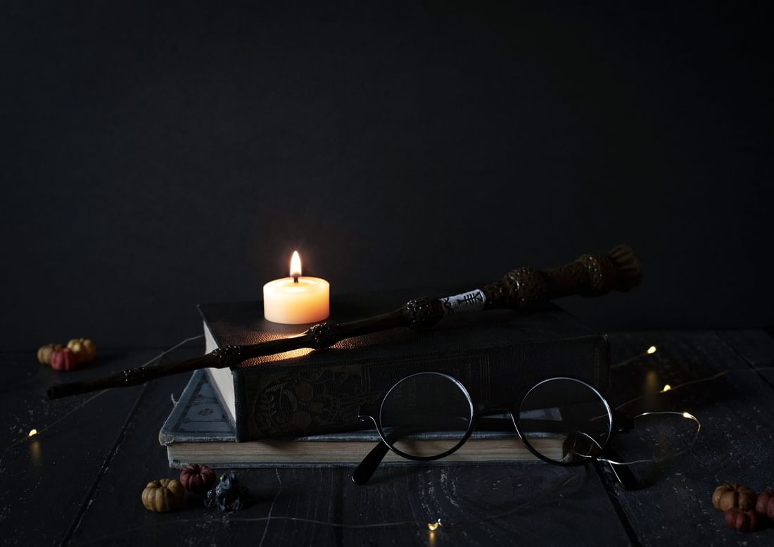Magic wand placed on old books by a lit candle at The Capital Hotel, Apartments and Townhouse