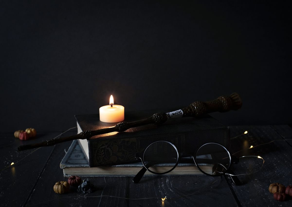 Magic wand placed on old books by a lit candle at The Capital Hotel, Apartments and Townhouse
