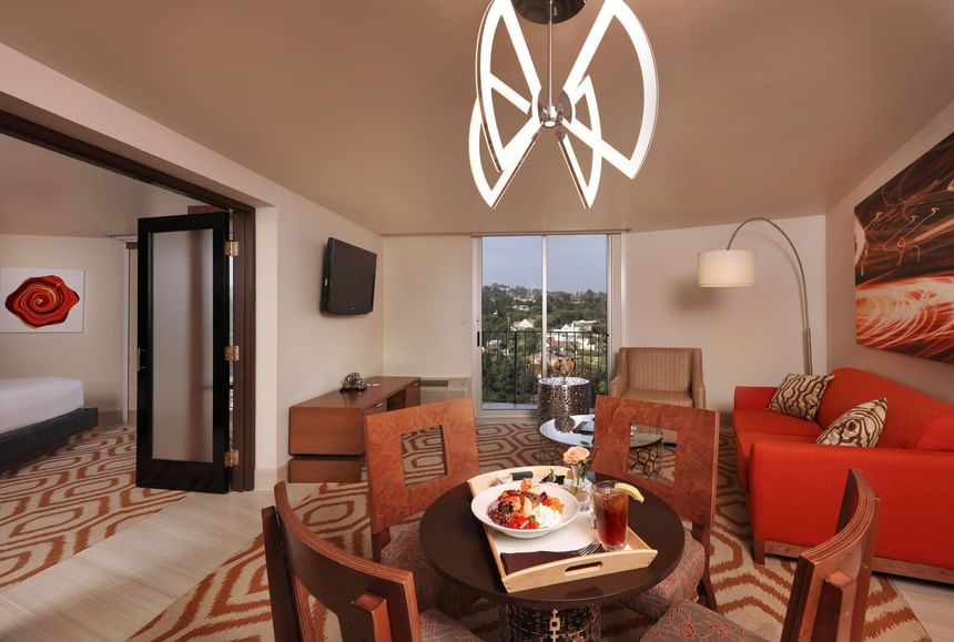 Fit for a King Suite, hotel rooms in Los Angeles featuring a red sofa, geometric rug, and a dining table at Hotel Angeleno